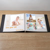 Open magnetic scrapbook album displaying photos of a one-year-old baby and a woman