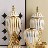 A pair of gold and white striped ceramic decorative vases with lid on a light background.