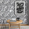 A framed print of a coiled snake in gray on a black and white zebra print wall.