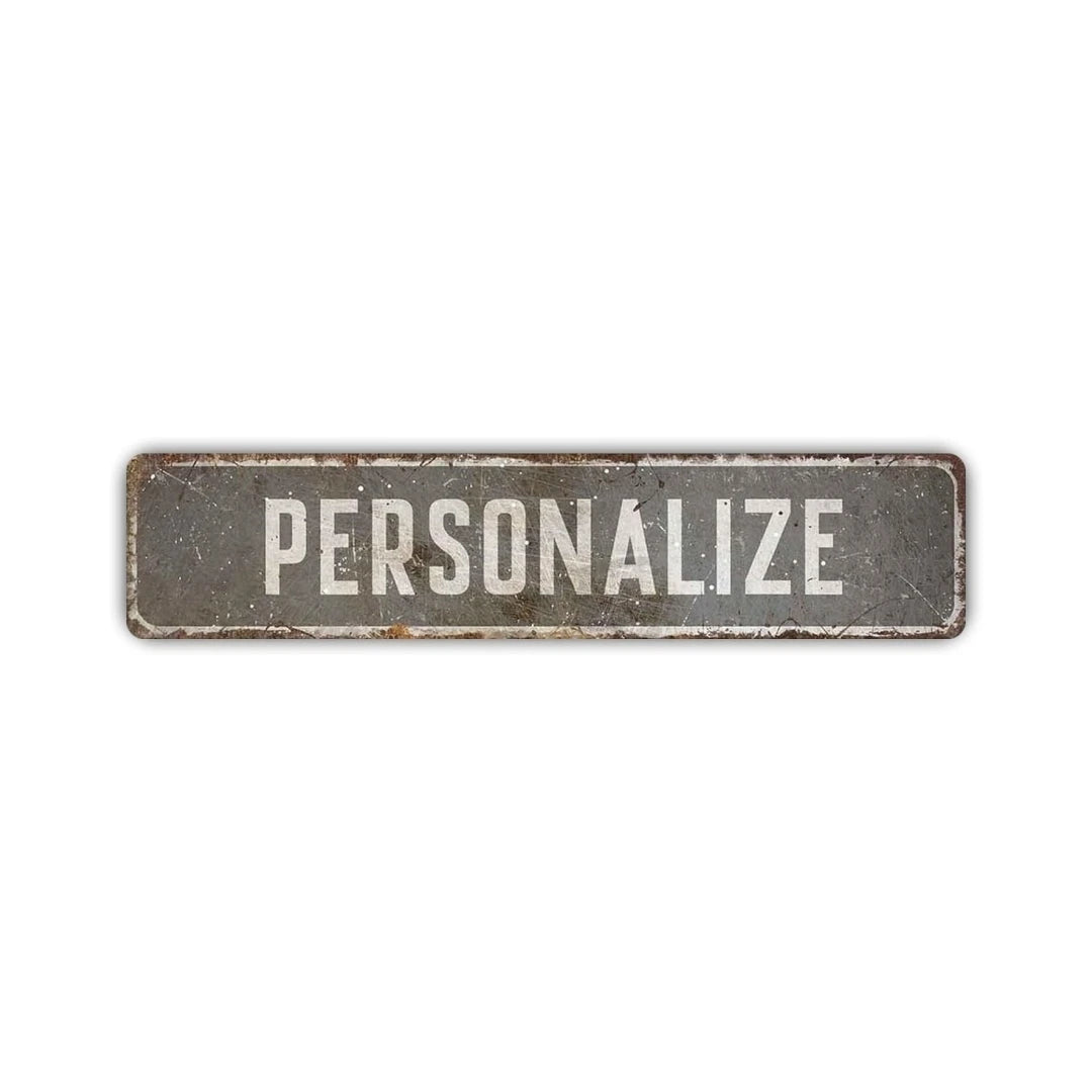 A rectangular, weathered gray aluminum street sign with the word PERSONALIZE engraved on it.