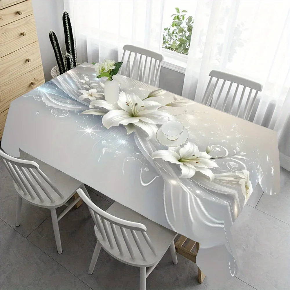 A white rectangular dining table set with a white floral tablecloth and matching chairs in a bright room.