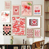 A gallery wall featuring pink and red floral art prints with hearts and bows on a white wall.