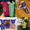 A collection of three plush toys featuring various colors and patterns, including a purple and gold Pokemon-style figure.