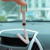 A hand holds a crystal letter keychain charm shaped like the letter I.