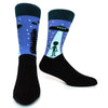 A pair of novelty crew socks featuring a blue night sky design with an alien silhouette and a tree print.