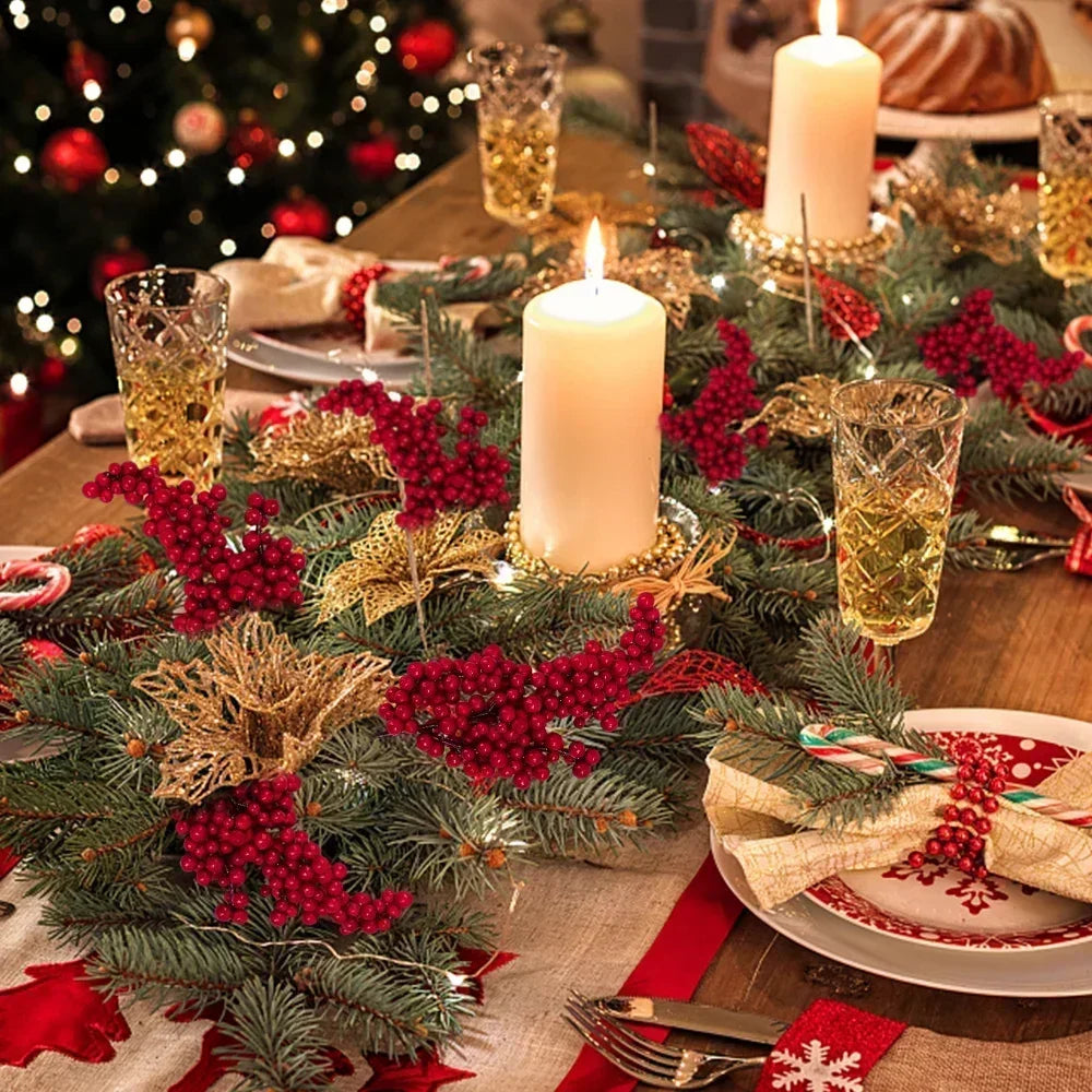 A festive holiday arrangement featuring green pine branches, red holly berries, and glowing candles on a wooden table.