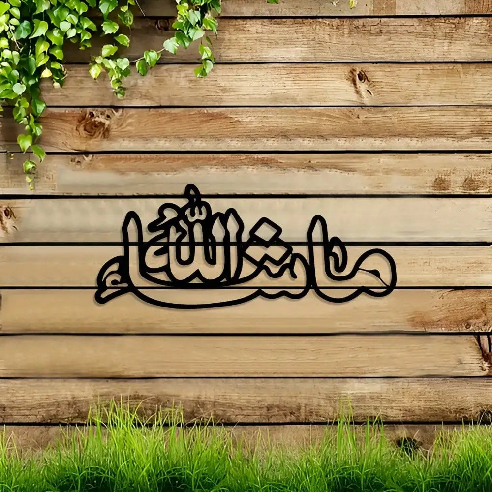 Black Arabic calligraphy design on a wooden wall with green foliage and grass in the foreground.