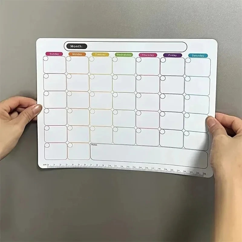 A magnetic fridge planner grid showing days of the week for monthly planning with empty squares.