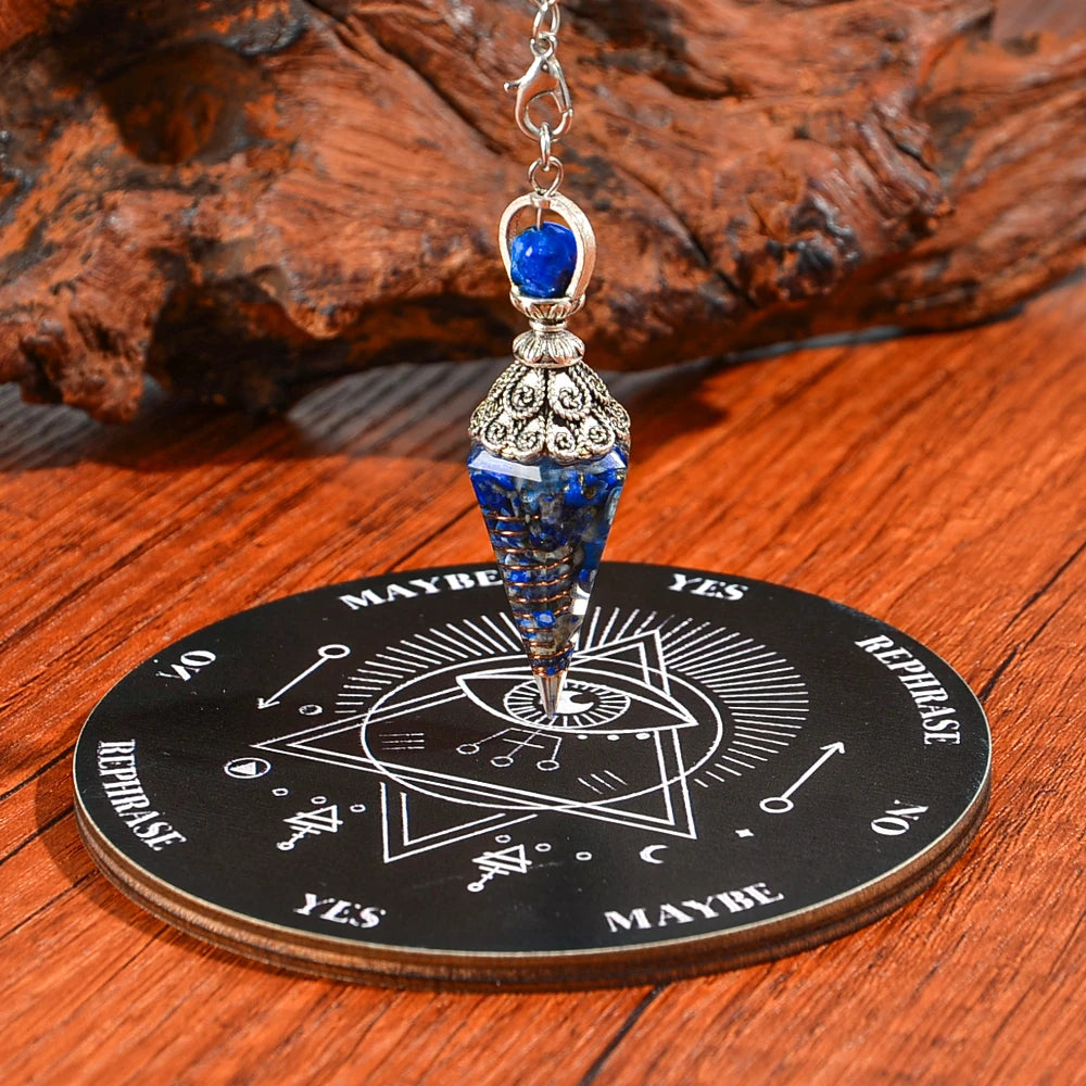 Silver pendant necklace with a blue crystal suspended over a wooden divination board