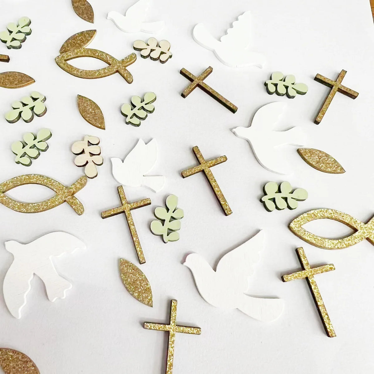A collection of gold and white dove and cross shapes used for faith and celebration party decor