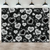 A black photo backdrop covered in white and silver glittering heart shapes, illuminated by overhead lights.