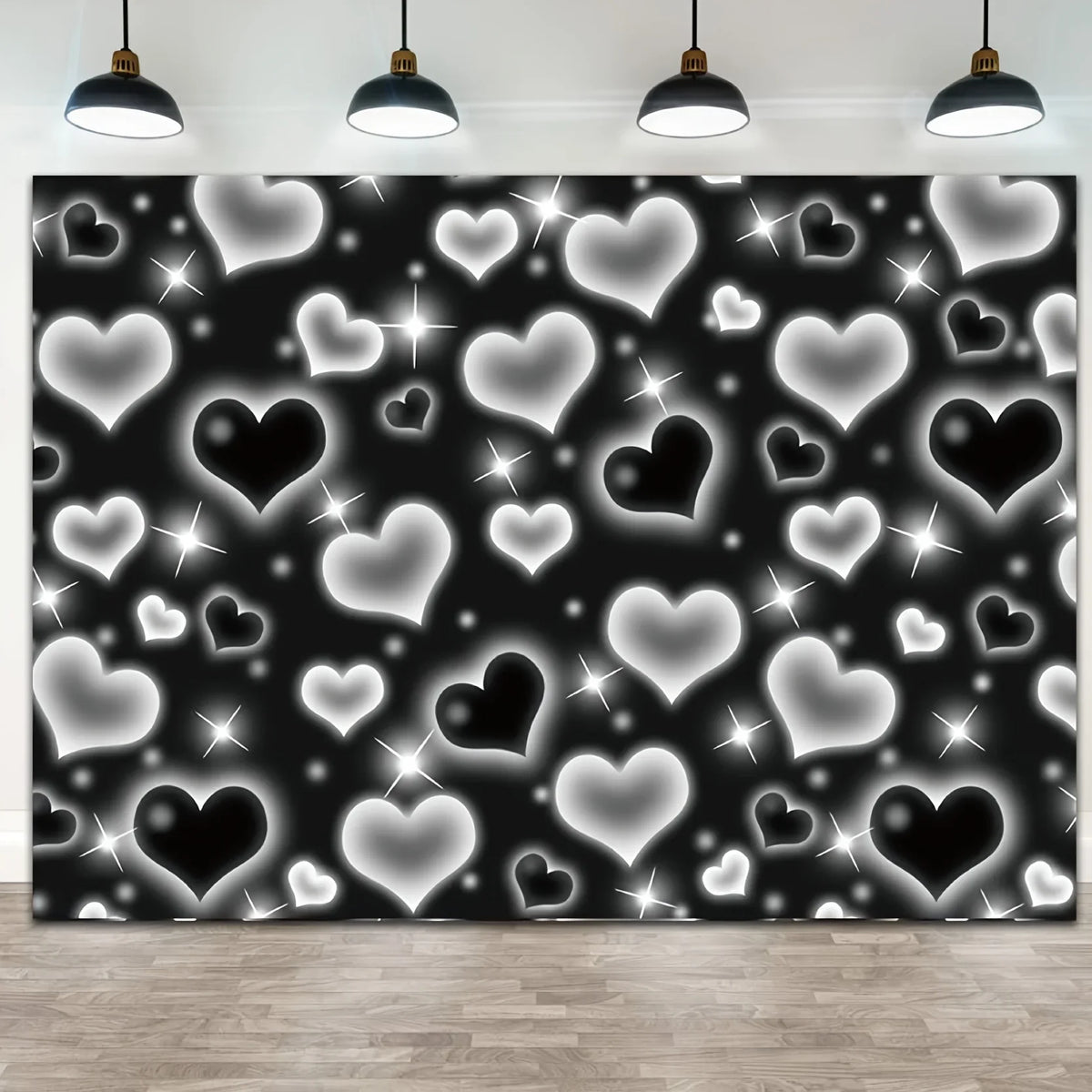 A black photo backdrop covered in white and silver glittering heart shapes, illuminated by overhead lights.