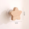 A light wood star-shaped decorative hook with a round mounting plate, shown next to a measurement scale.