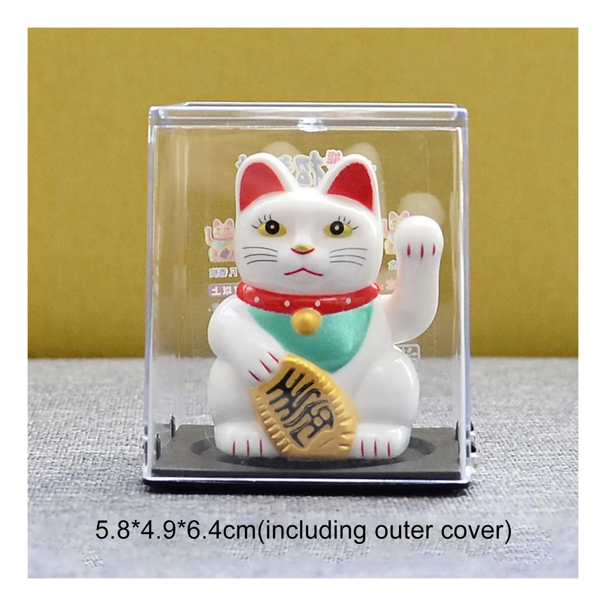A white cat figurine with red ears and a gold coin, displayed in a clear plastic case.