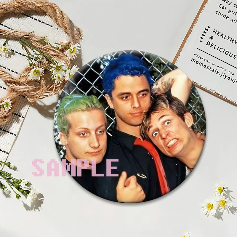 A set of collectible brooches featuring portraits of three individuals with brightly colored hair against a dark background.