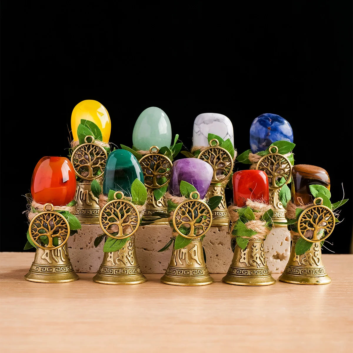 A collection of colorful natural crystals, including yellow, green, purple, and blue stones, set in brass tree-shaped chimes.