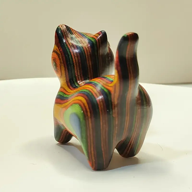 Hand-painted wooden sculpture of a kitten with swirling stripes of brown, orange, and green colors.