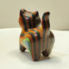 Hand-painted wooden sculpture of a kitten with swirling stripes of brown, orange, and green colors.