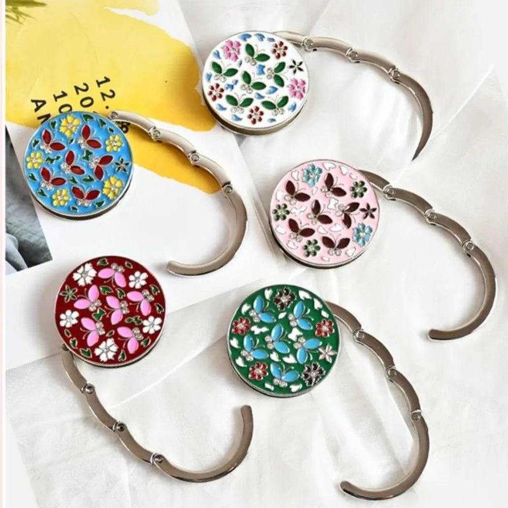 A collection of floral crystal handbag hooks with silver-toned metal arms and colorful round crystal accents.