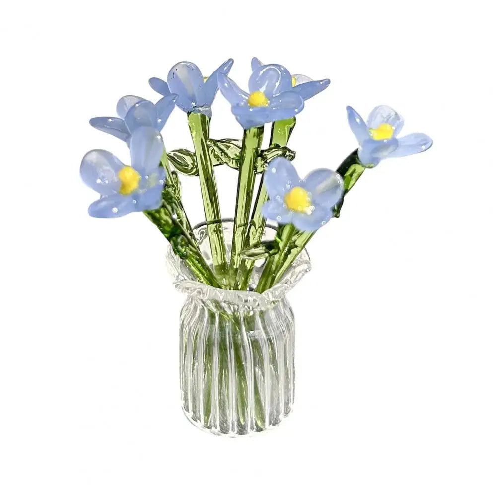 A bouquet of light blue and yellow hand-blown glass flowers in a clear glass vase.