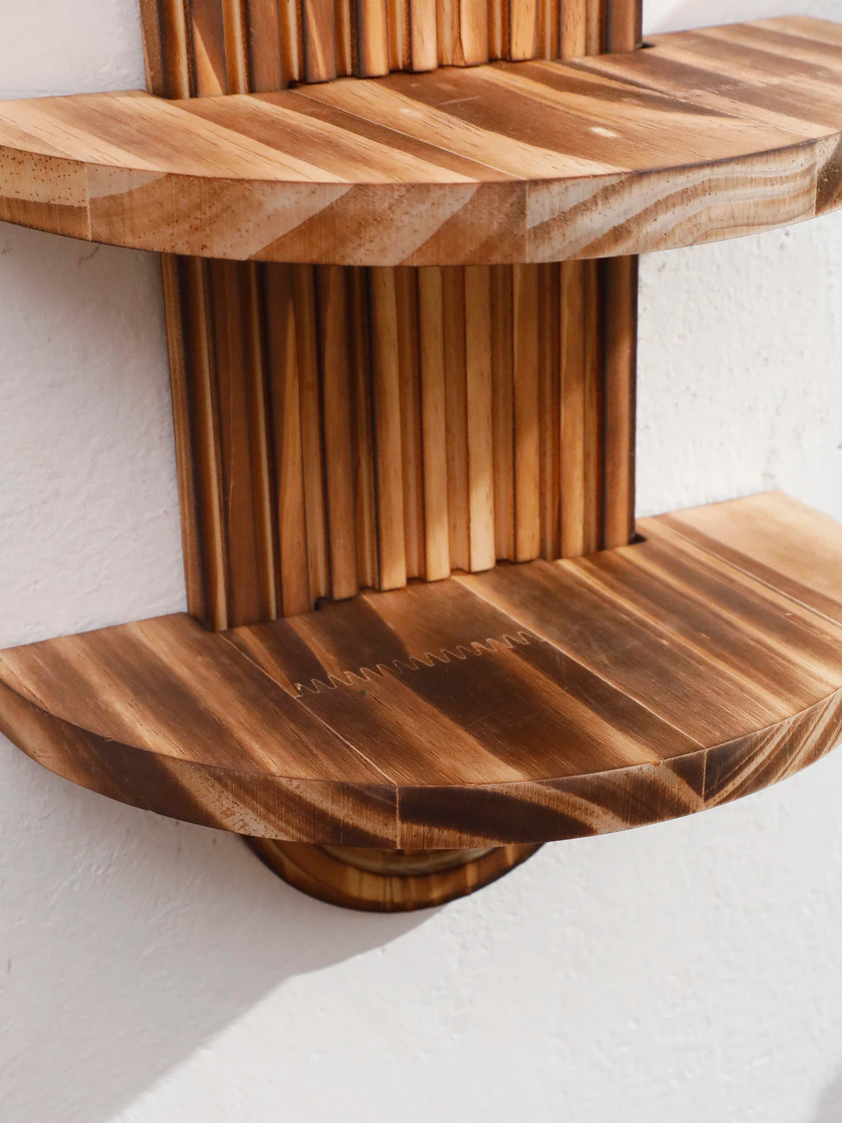 Two wooden wall shelves with striped grain patterns mounted on a white wall.