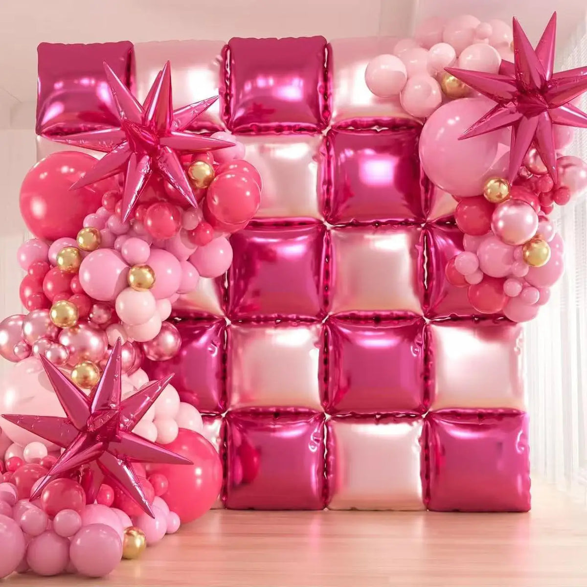A wall display made of square pink and magenta foil balloons shaped like stars and cubes for celebrations