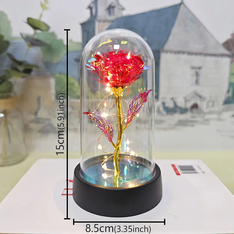 A glass dome containing a red rose with an LED light, displayed on a white surface.