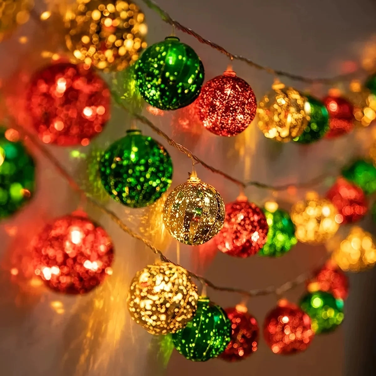 A close-up of festive LED fairy lights with colorful, shimmering ornaments hanging on wires.
