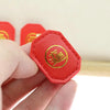 A hand holds a red felt charm shaped like a turtle with gold Chinese characters on it.