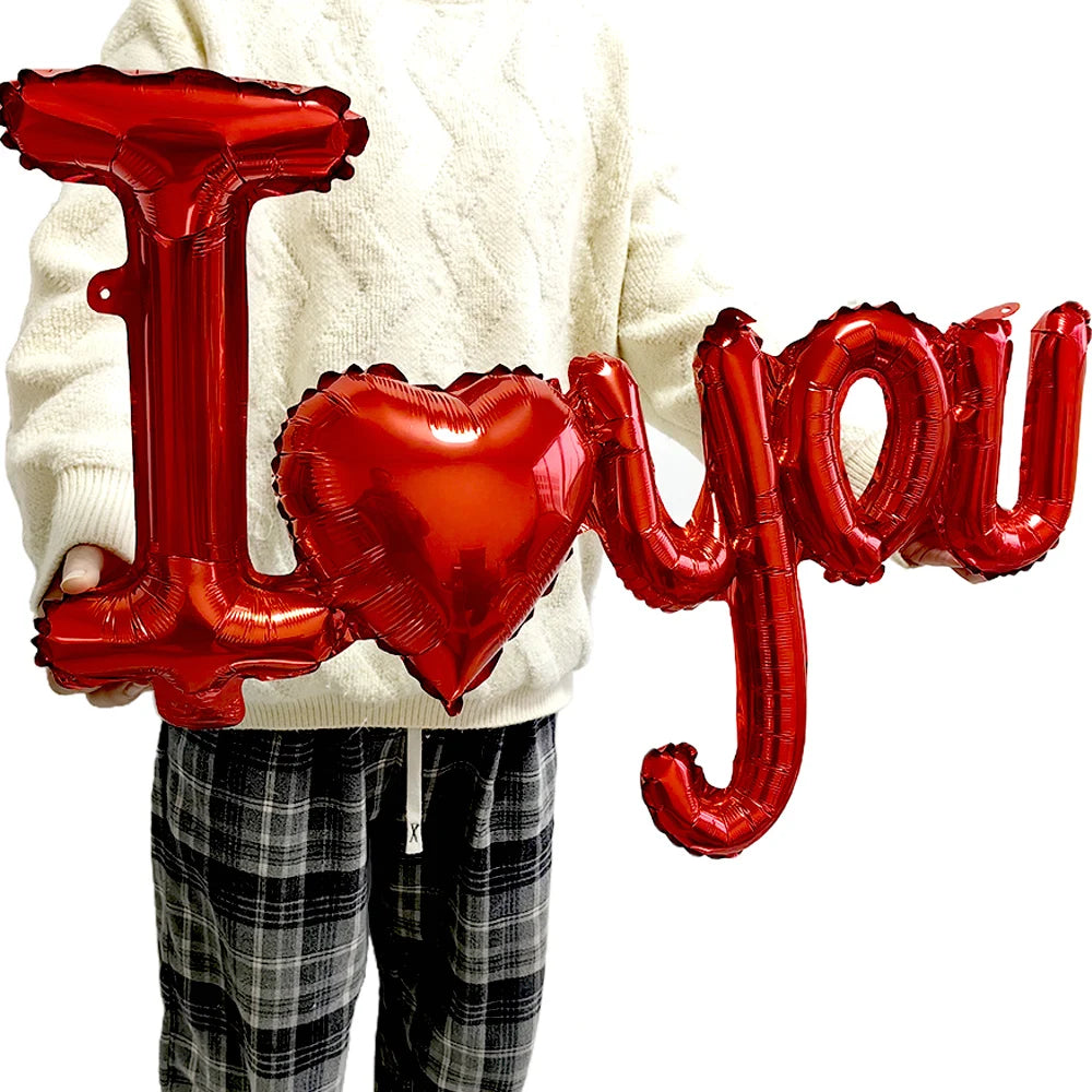 Red foil letter balloons spelling I love you and a heart held by a person wearing a cream sweater.