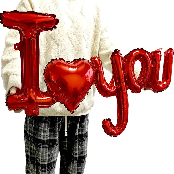 Red foil letter balloons spelling I love you and a heart held by a person wearing a cream sweater.