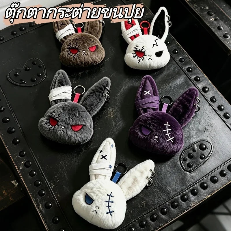 A collection of dark and light colored bunny plush keychains with various expressions and accessories displayed on a black su