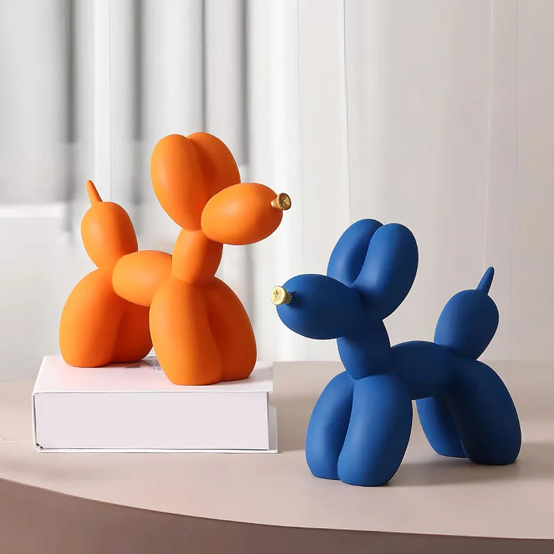 A pair of orange and blue balloon dog resin sculptures displayed on a white surface.