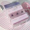 Tres cajas de almacenamiento minimalistas rosas con tapas decorativas y pegatinas, exhibidas sobre una superficie de lunares 