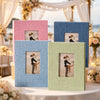 A display of linen photo albums in various shades of blue, pink, and green set up for an event.