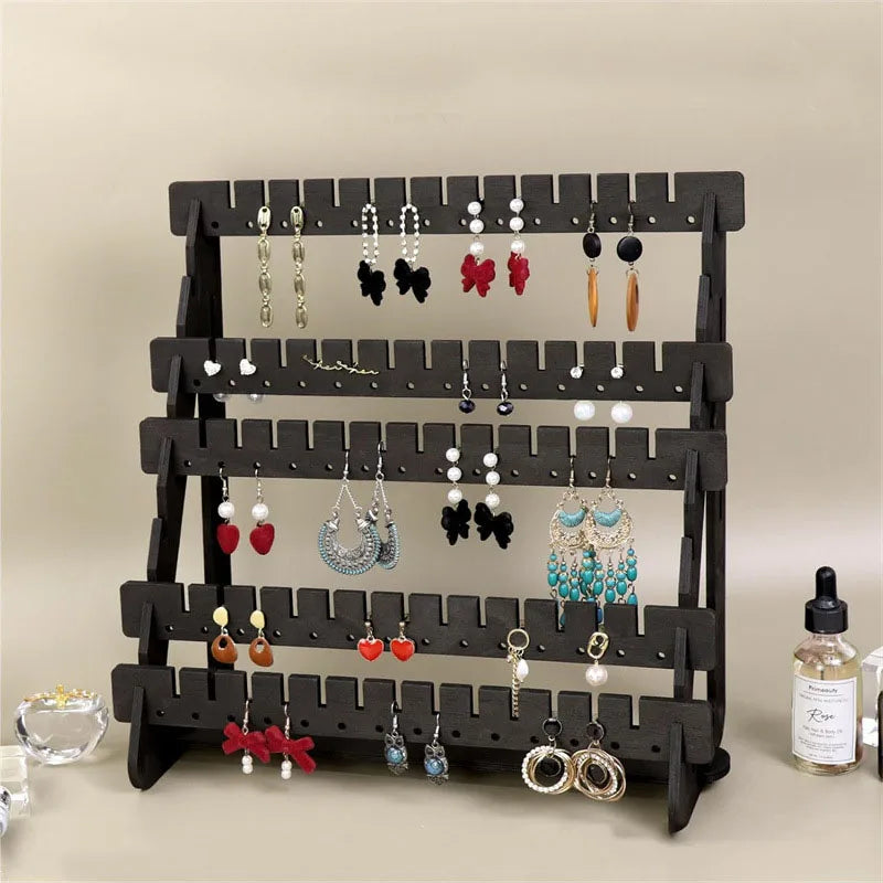 A black wooden multilayer organizer displaying various silver and colored earrings and jewelry.