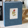 A blue linen cover photo album with a square window displaying a red rose illustration and the words Flower language.