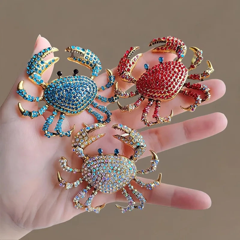 A set of three vintage marine life brooch pins featuring colorful crab designs on a hand.