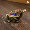 Figurita de sapo chino dorado con gemas coloridas, sobre una superficie de madera.