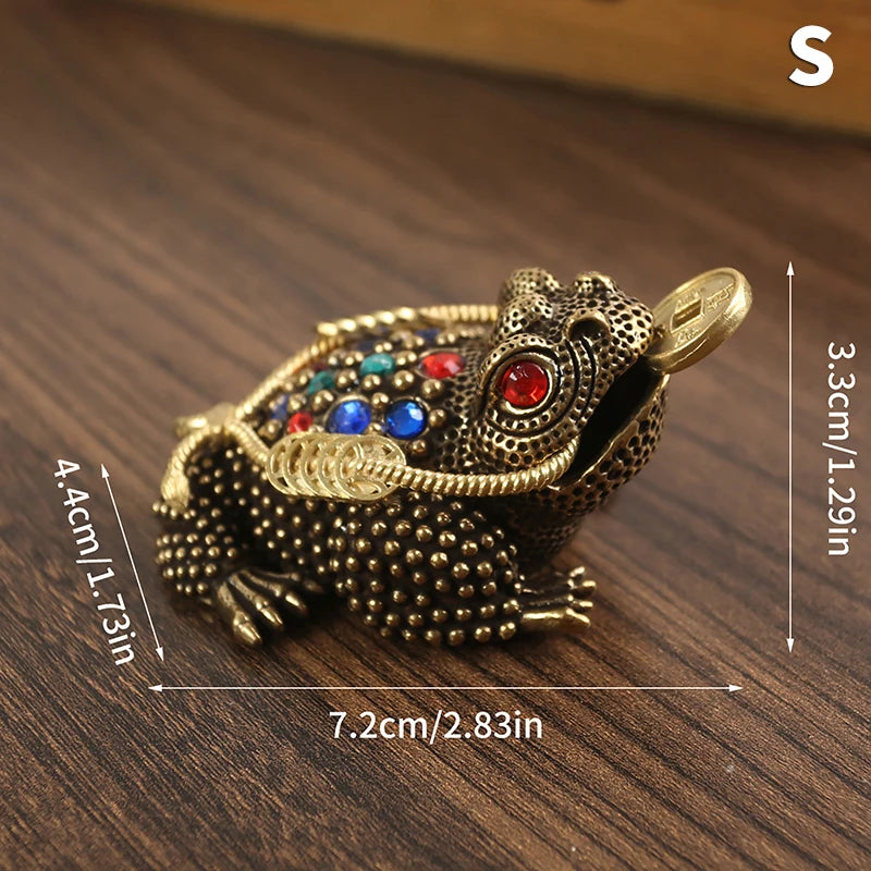 Figurita de sapo chino dorado con gemas coloridas, sobre una superficie de madera.