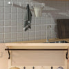 A kitchen wall featuring wooden shelves and metal hooks used for hanging coats, bags, and towels.