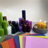 A collection of colorful honeycomb beeswax candles and various colored honeycomb paper sheets.