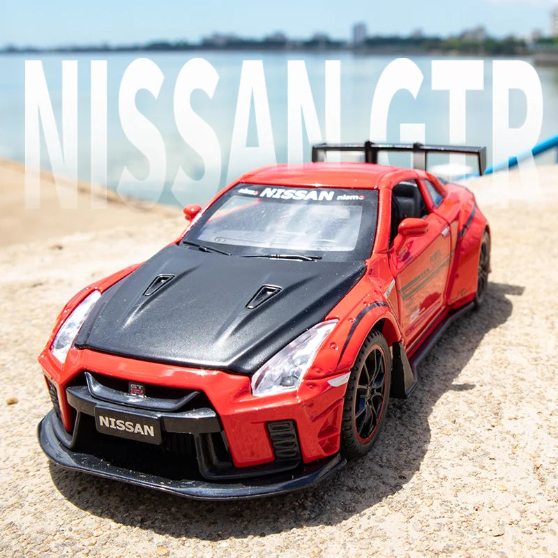 A red Nissan GT-R sports car model is displayed on a sandy surface with water in the background.
