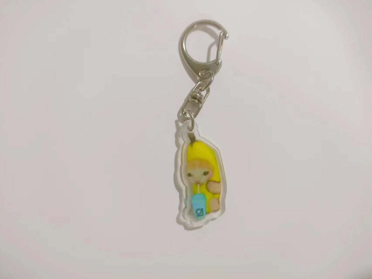 Silver acrylic keychain featuring a yellow banana cat figurine.