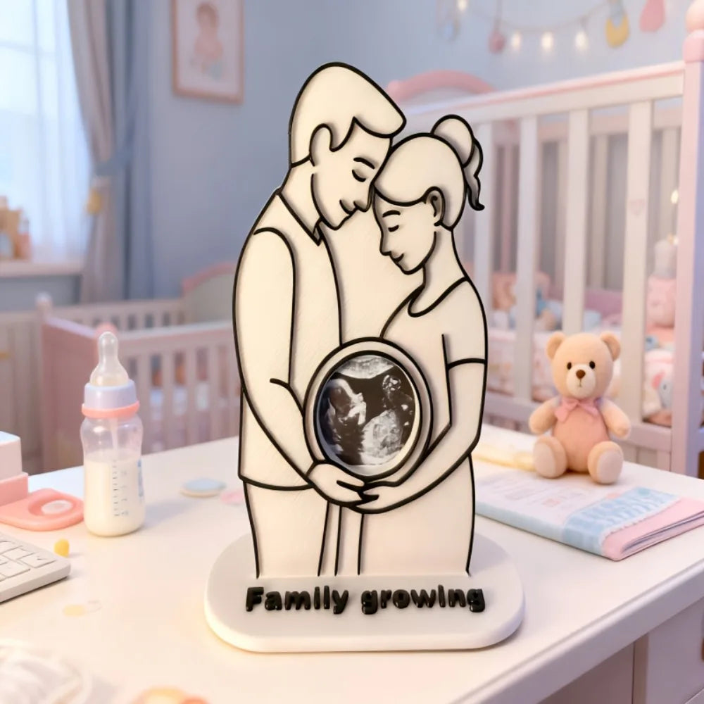 A white silhouette of a mother and baby embracing, with a circular ultrasound photo inside, on a white base.