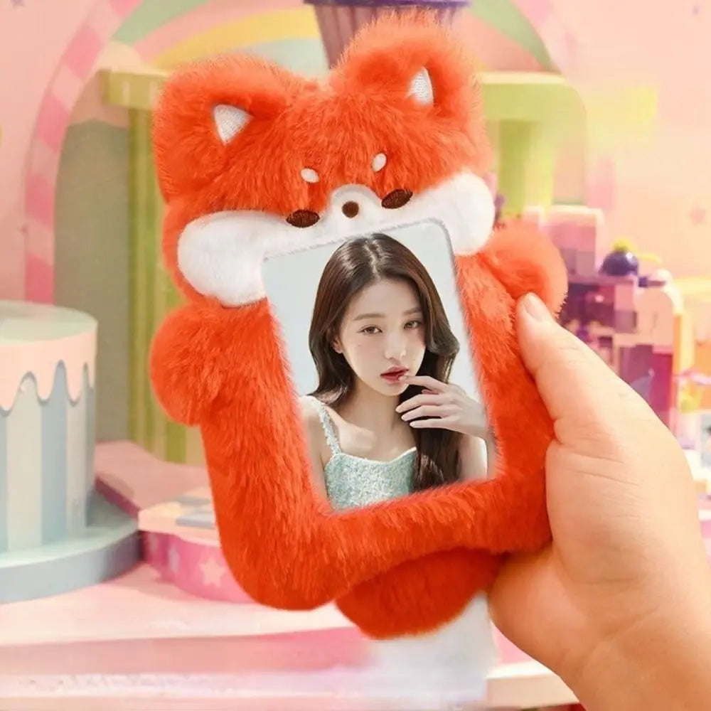 An orange fox plush toy is used as a frame to hold a smartphone displaying a person's face.