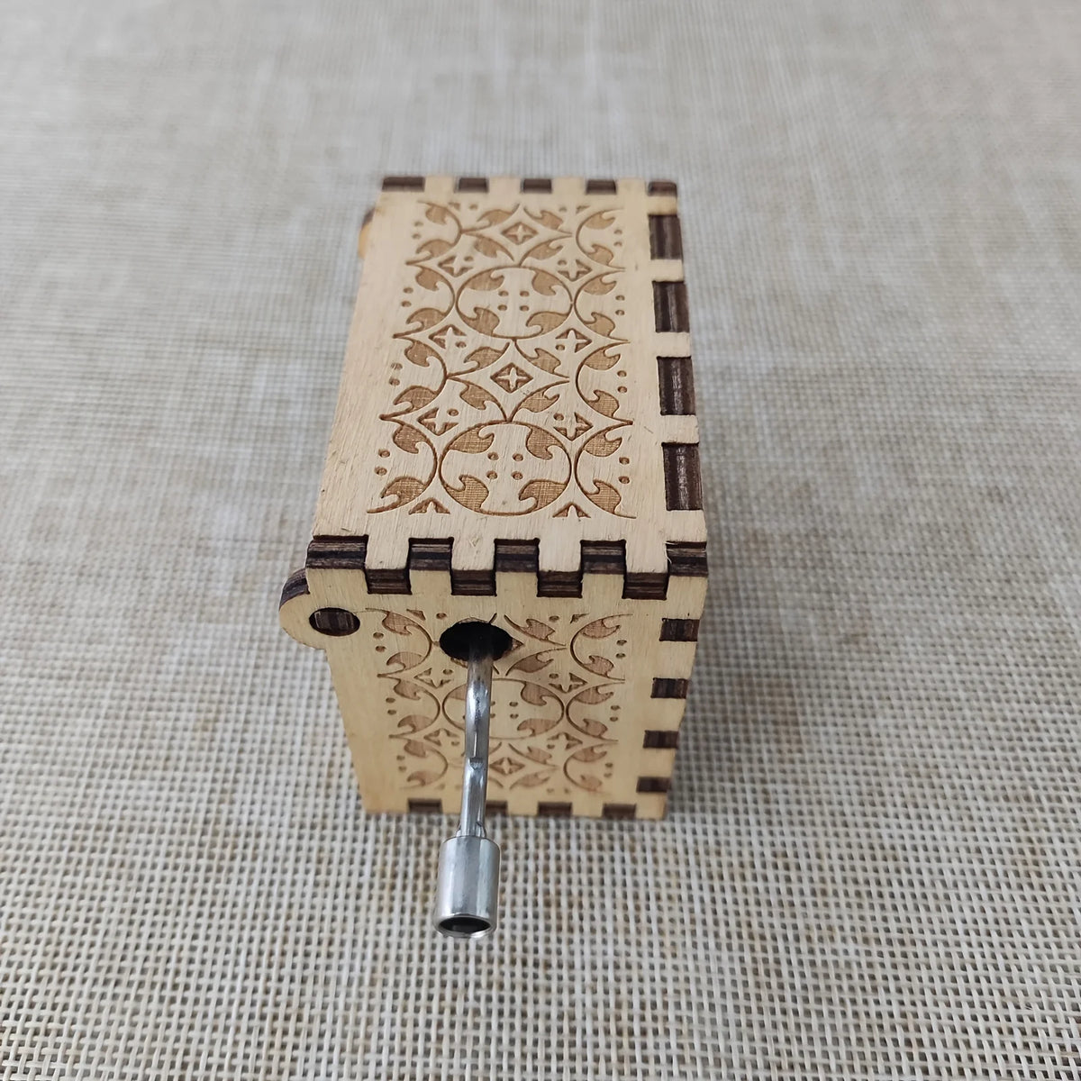 Antique carved wooden music box with decorative patterns and a metal hinge