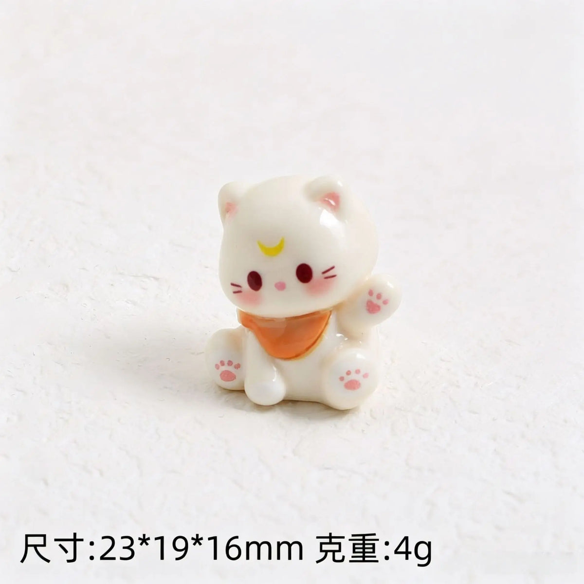 A small white resin cat keychain with pink accents and an orange collar.