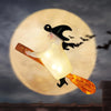 A floating LED candle shaped like a witch with a magic wand, suspended against a large moon background.