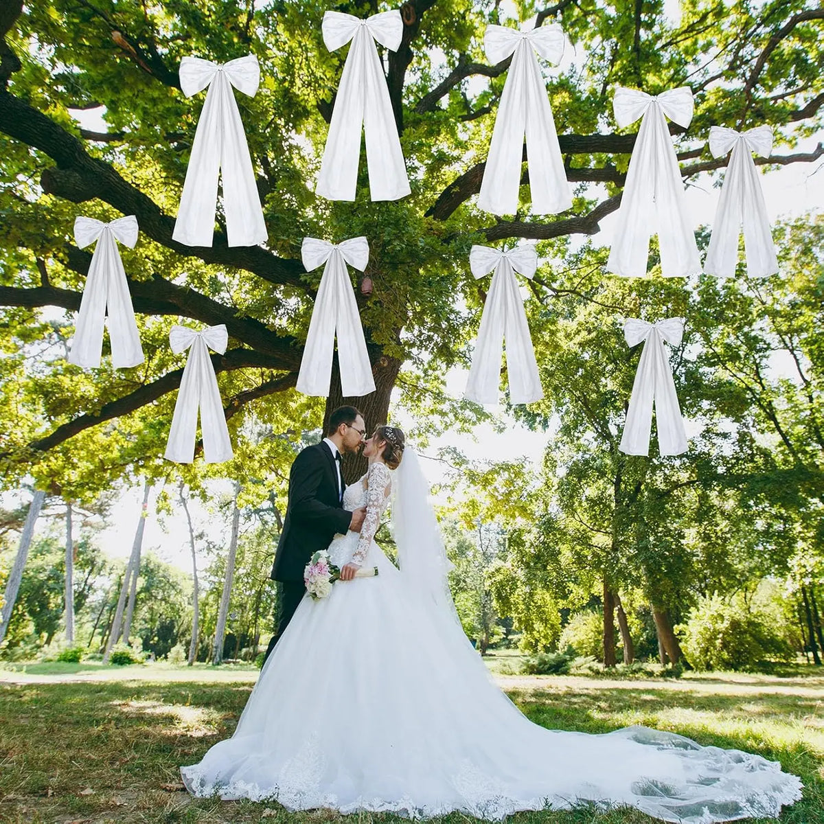 Un(e) marié(e) et mariée s'embrassent sous une canopée de nœuds de satin blancs suspendus sur des branches d'arbre vertes en 